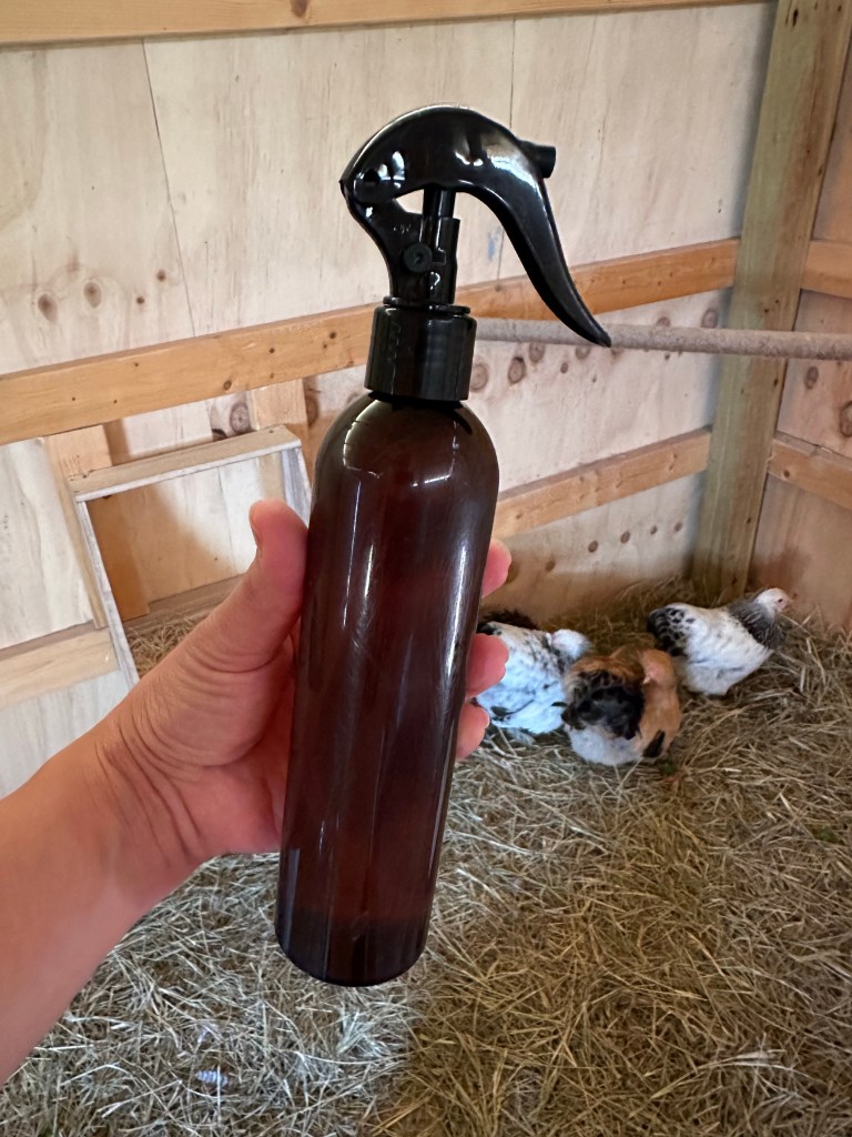 Brown spray bottle inside a wood chicken coop, with chickens.